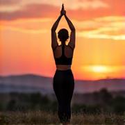 Woman performing yoga pose at sunrise outdoors with a vibrant sky